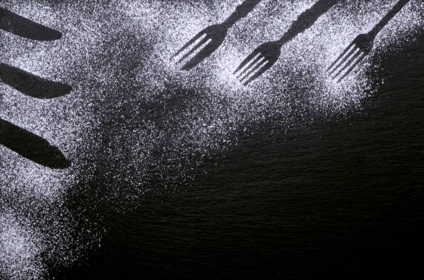 istock Black and white background design with figures of kitchen flatware on the snow or flour 1074995160
