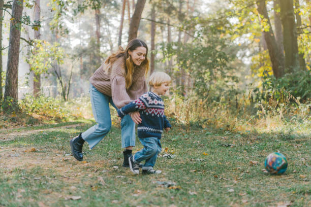 istock Little boy playing soccer  with mom in forest 1074995346