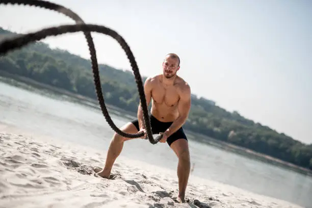 Photo of Strong man doing workout with battle rope