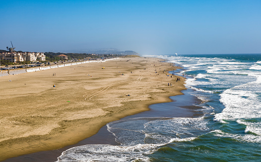 San Francisco, USA - January 26, 2020: Silhouettes of happy people enjoying on Ocean Beach in winter. Famous tourist destination. Romantic sunny view of wet sand and tide. Amazing panorama. Seaside