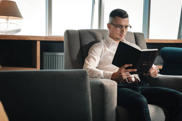 istock Smart young man wearing glasses reading the Holy Bible 1075011764