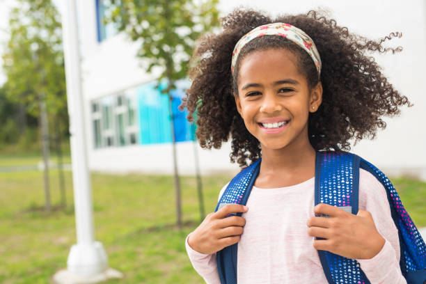 istock cheerful african american primary school girl with backpack 1075025556