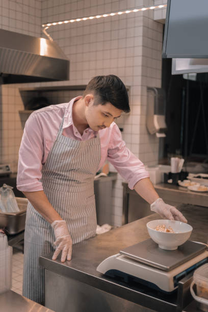 istock Dark-haired chef measuring salad before serving it to client 1075029242