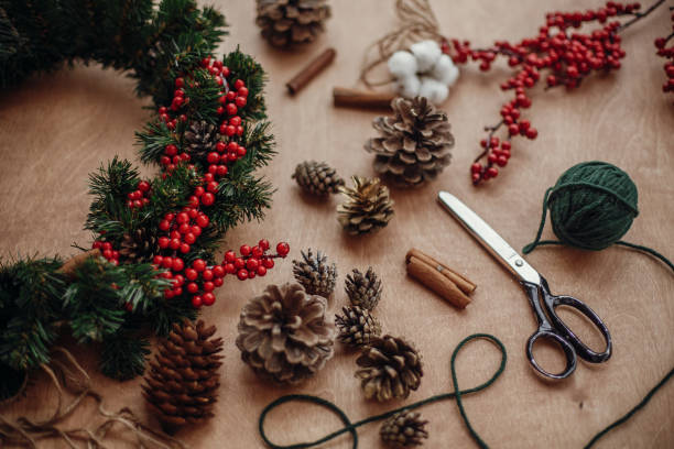 istock Rustic Christmas wreath. Fir branches, wreath,red berries, pine cones,thread, scissors, cinnamon, cotton on rustic wooden background. Making christmas wreath at 
 holiday workshop 1075039746