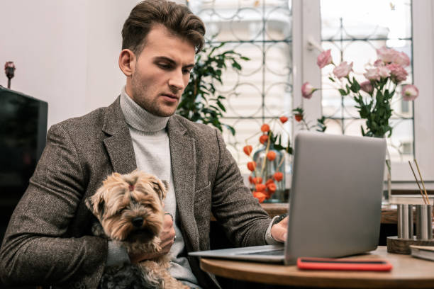 istock Young man holding his dog working remotely 1075041278