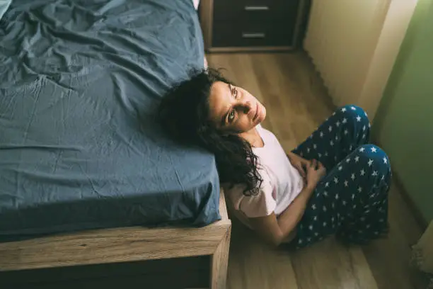 Mid age woman having problems sitting in her bedroom