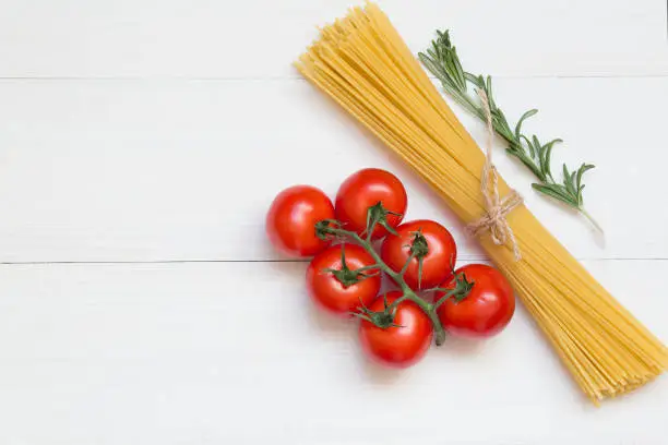 Spaghetti ingredients, tomato, rosemary, concept on white background, top view