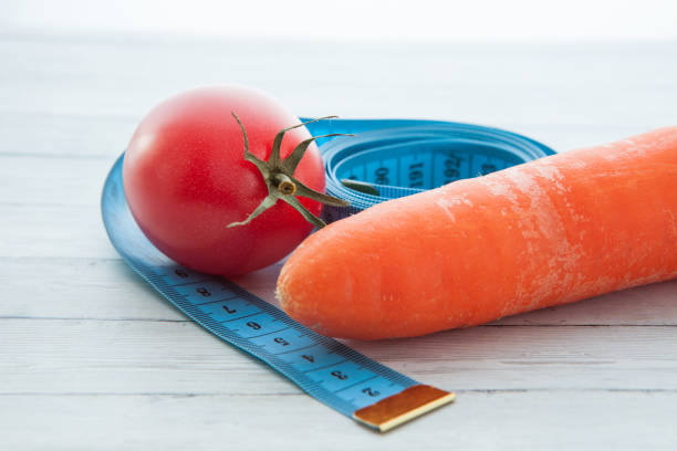 測定テープ、ジューシーなトマトとニンジン、健康的な食事と減量の概念 - instrument of measurement vegetable measuring exercising ストックフォトと画像
