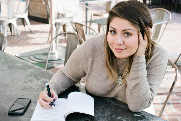 Young Latina Female Writes Down Her 2019 New Years Resolutions A young woman at an outdoor cafe writes down her 2019 New Years Resolutions 2019 new year resolution stock pictures, royalty-free photos & images