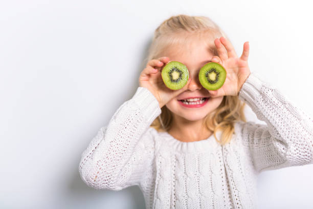 istock Cute girl 4-5 year old posing in studio with fruit kiwi 1075108940