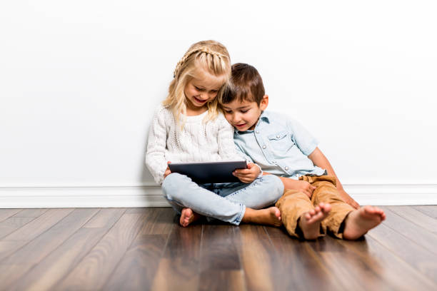 szczęśliwe rodzeństwo dziecko bawi się tabletem pc razem - sofa indoors childhood technology zdjęcia i obrazy z banku zdjęć