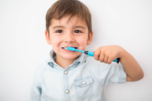 smiley junge reinigt ein zähne isoliert auf grauem hintergrund - child brushing human teeth brushing teeth stock-fotos und bilder