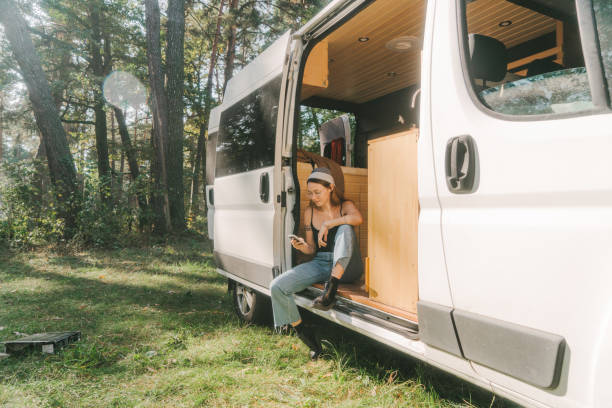 istock Woman sitting in camper van and using smartphone 1075111012