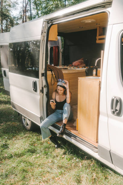 istock Woman sitting in camper van and using smartphone 1075111026