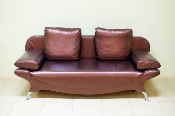 istock Leather sofa with pillows near the light wall. 1075118770