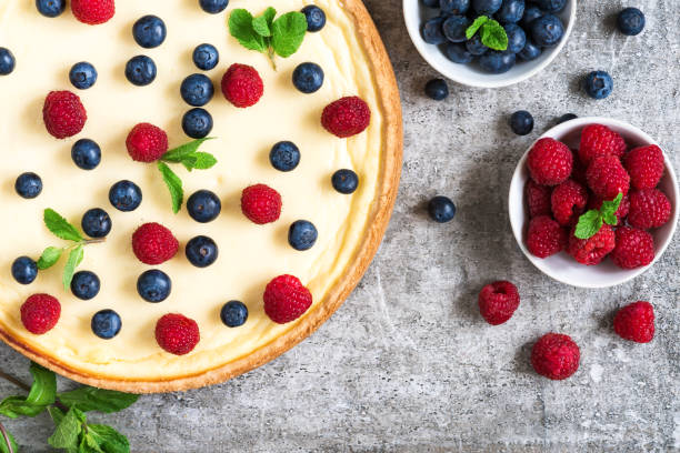istock Classic New York cheesecake with fresh berries and mint on stone background, top view 1075129998