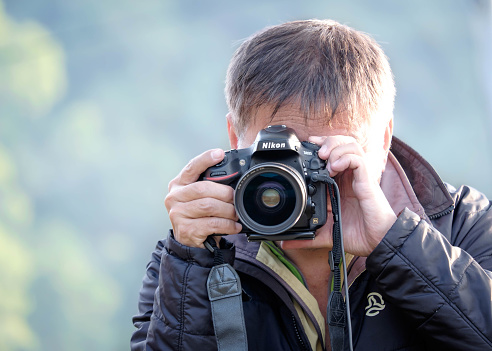 TAIWAN, HUALIEN - DECMEBER 2014 :Portrait of a photographer covering his face with the camera.