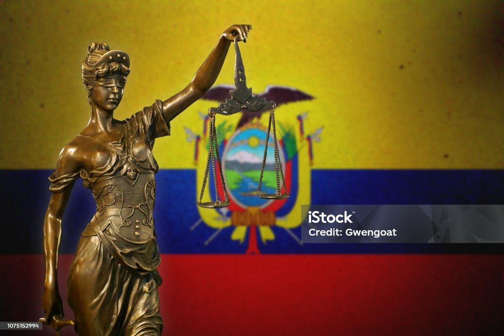 Lady Justice before an Ecuadorean flag Close-up of a small bronze statuette of Lady Justice before a flag of Ecuador. Law Stock Photo