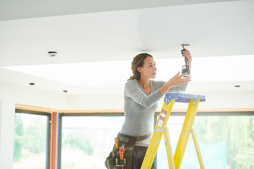 female electrician installing downlights