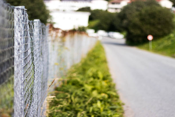 A rural road with a perimetral wire fence on the sidewalk, selective focus, copy space.