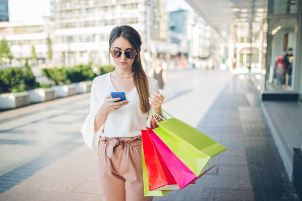 istock Young woman with shopping bags using smartphone. 1075193766