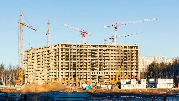 istock Construction of a new multi-storey building surrounded by forests. Construction cranes against the blue sky. 1075210024