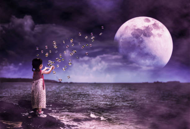 istock Asian girl playing with soap bubbles. Super moon behind partial cloud on sky. 1075273776