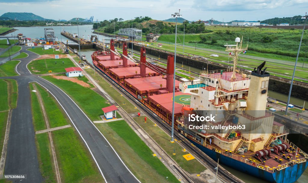 Cargo ship passes through lift locks of the Panama Canal. Big cargo ships make pass through the Panama Canal locks.  This everyday event, provides income from both fees and tourism for the whole country. Panama Canal Stock Photo