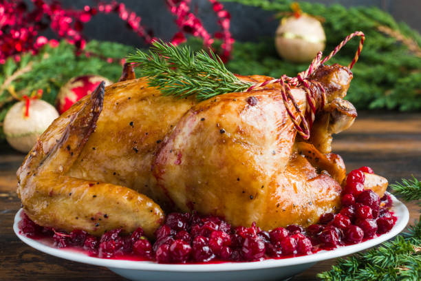 Whole rosted chicken with cranberry sauce on white plate on wooden table with Christmas decoration Whole rosted chicken with cranberry sauce on white plate on wooden table with Christmas decoration sauces table turkey christmas stock pictures, royalty-free photos & images