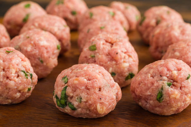 istock Uncooked raw meatballs on wooden cutting board 1075357876