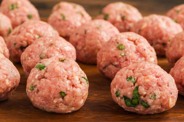 istock Uncooked raw meatballs on wooden cutting board 1075357898