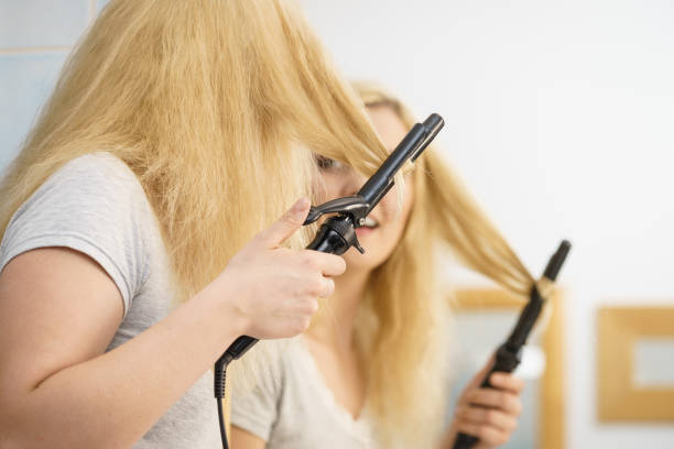 istock Woman using hair curler 1075358426