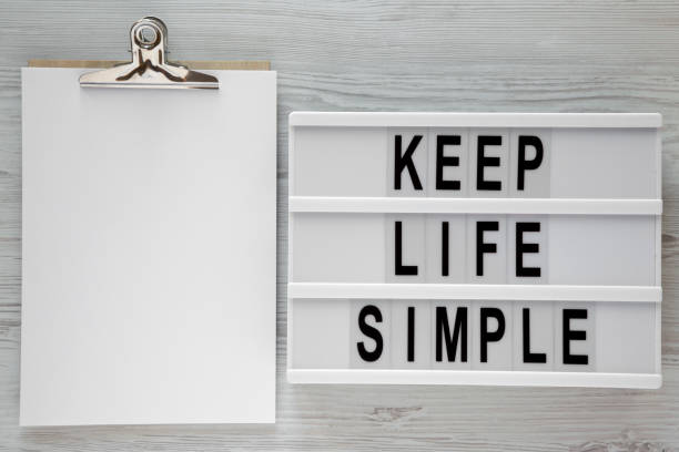 istock 'Keep life simple' words on lightbox, clipboard over white wooden background, top view. Flat lay, from above, overhead. Text area. 1075370208