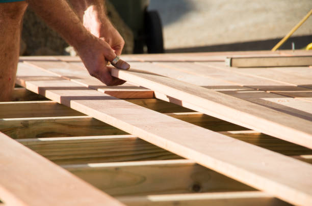 Man placing a plank of wood in a deck home renovation Man placing a plank of wood in a deck home renovation on a warm sunny day decking stock pictures, royalty-free photos & images