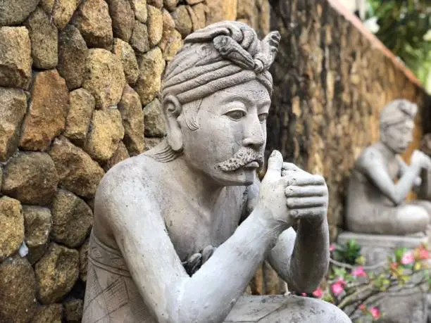 Sculpture of praying balinese man sitting in a crossed leg manor located in Nusa Dua, Bali