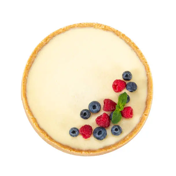 Whole classic cheesecake with raspberries, blueberries and mint isolated on white background. Top view.