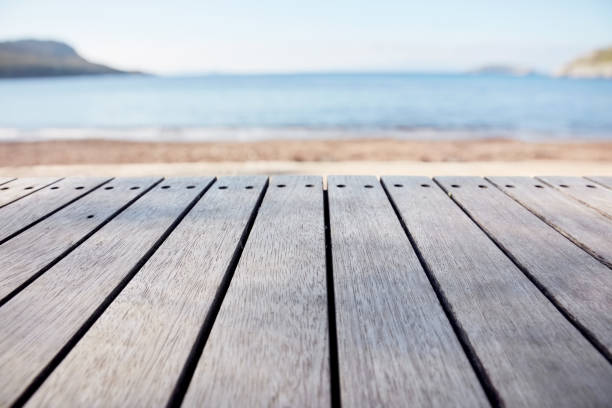 Empty wooden deck table on blurry sea and beach background. Copy space for product display and composite images.