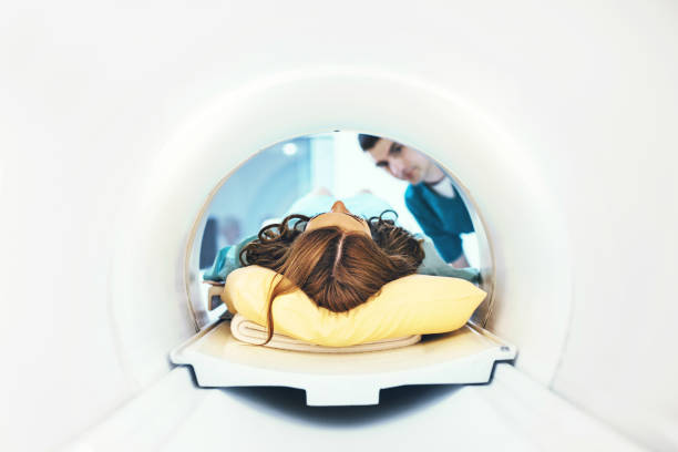 Entering MRI scan. Unrecognizable female patient entering a mri scan while technician standing and looking at her. hair length stock pictures, royalty-free photos & images