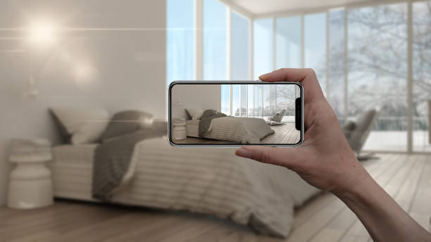 istock Hand holding smart phone, AR application, simulate furniture and interior design products in real home, architect designer concept, blur background, minimalist bedroom with panoramic window 1075416274
