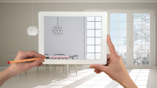 istock Hands holding and drawing on tablet showing classic bedroom kitchen with dining table CAD sketch. Real finished interior in the background, architecture design presentation 1075416296