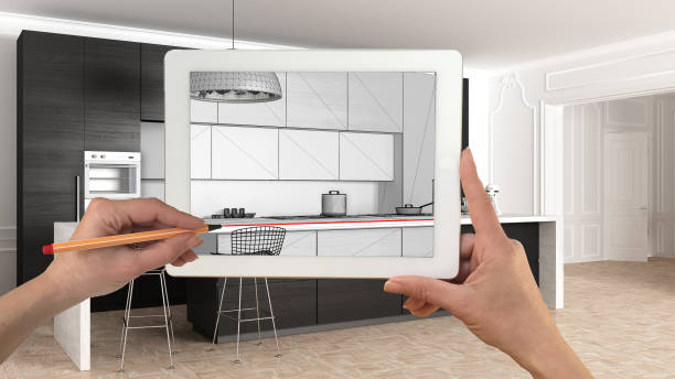 istock Hands holding and drawing on tablet showing modern kitchen in classic apartment interior sketch. Real finished minimalist interior in the background, architecture design presentation 1075416318