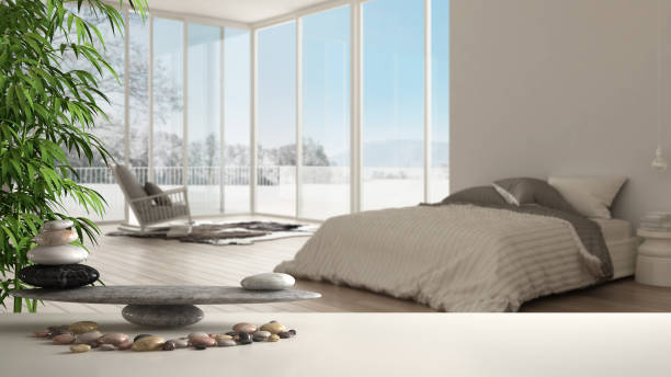 Wooden vintage table or shelf with stone balance, over blurred minimalist bedroom with big panoramic window, carpet and armchair, feng shui, zen concept architecture interior design Wooden vintage table or shelf with stone balance, over blurred minimalist bedroom with big panoramic window, carpet and armchair, feng shui, zen concept architecture interior design feng shui photos stock pictures, royalty-free photos & images