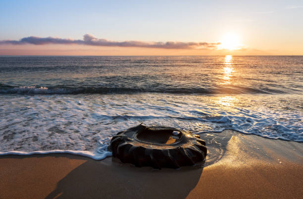 istock Tyre on the beach. Beautiful sunrise and dirty beach. 1075429062