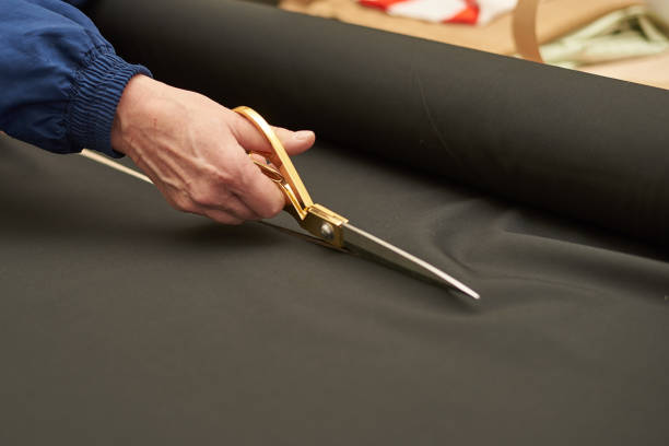 istock Woman cuts black material with Golden scissors. 1075430032