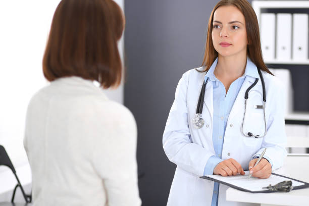 istock Doctor and  patient  discussing something while standing near reception desk in emergency hospital. Physician at work in clinic. Medicine and health care concept 1075443530