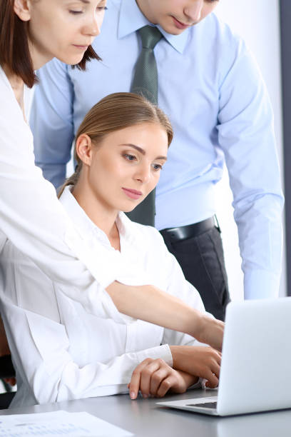 istock Group of business people using laptop computer while standing in office. Meeting and teamwork concept 1075443850