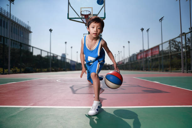 ładny mały chłopiec gra w koszykówkę - child basketball uniform sports uniform zdjęcia i obrazy z banku zdjęć