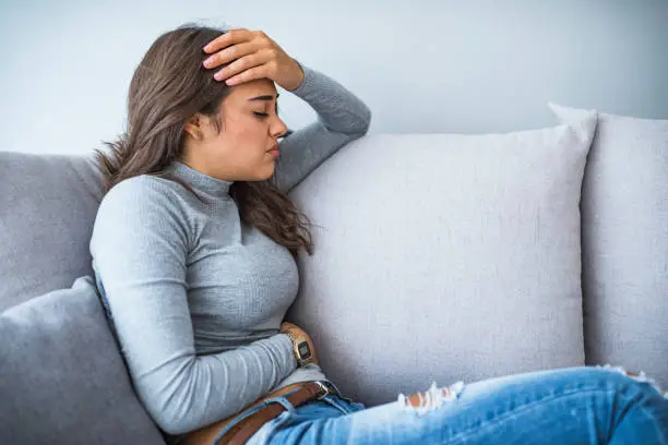Photo of View of young woman suffering from stomachache on sofa at home