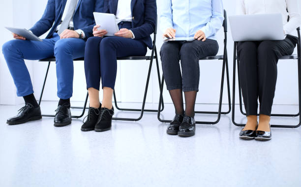 istock Group of business people sitting in office and waiting for job interview while using gadgets, close-up. Conference or training concepts 1075451982