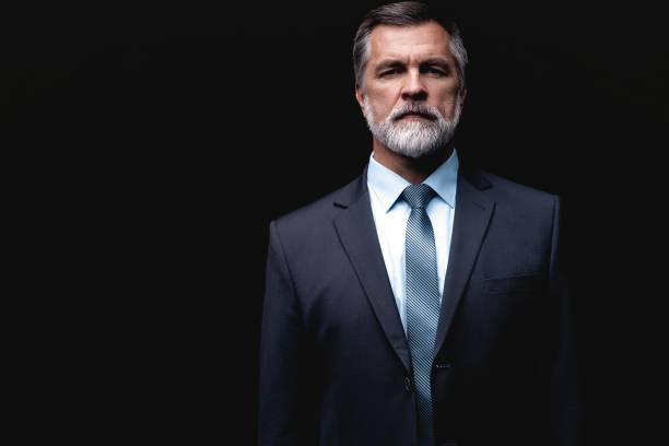 istock Handsome mature business man isolated on black background 1075457040